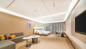 Une chambre d’hôtel moderne équipée d’un canapé, d’un lit, d’une table à manger et d’un téléviseur.