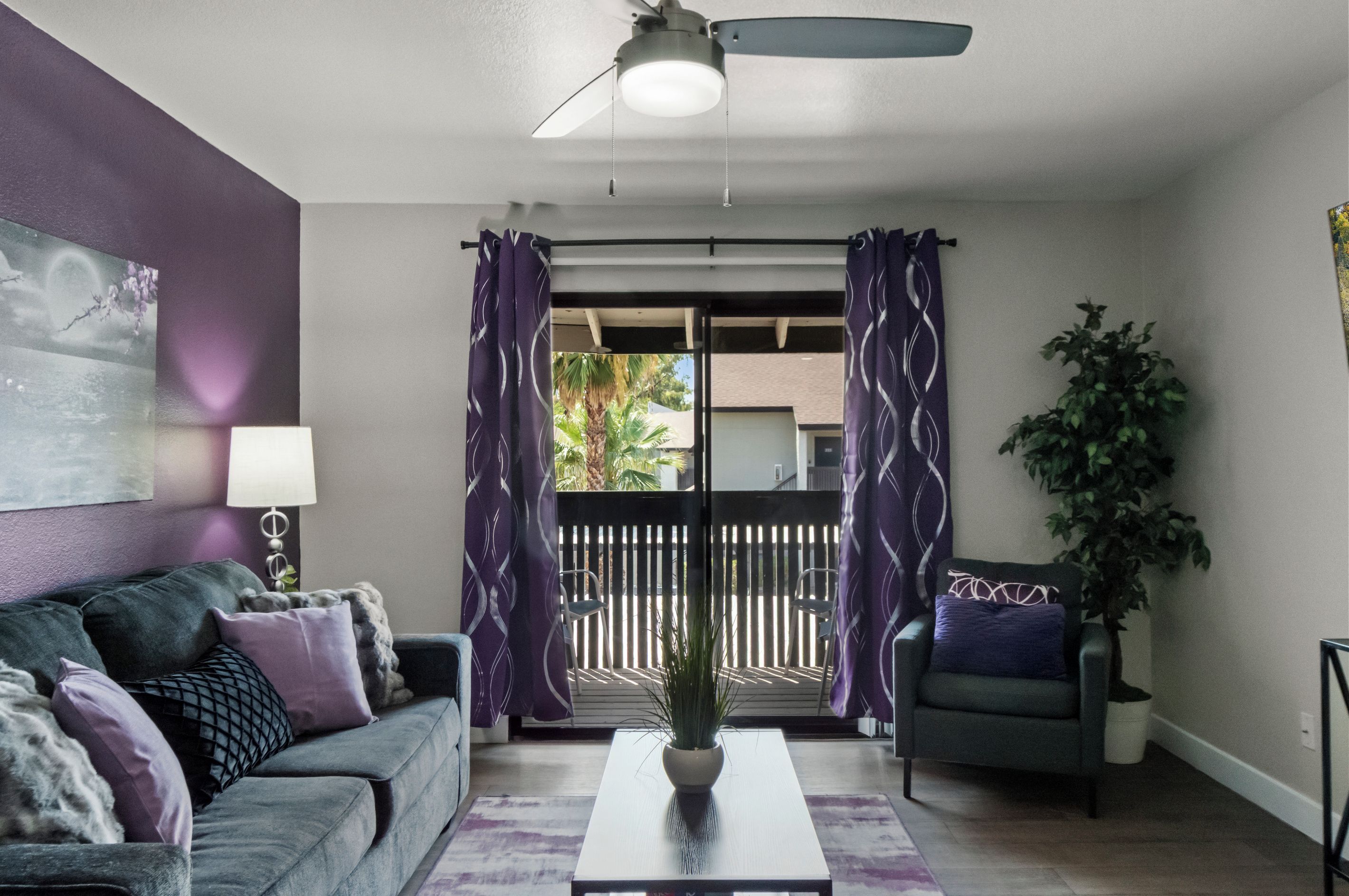 A living room with a sofa, a coffee table, a lamp, and a plant.