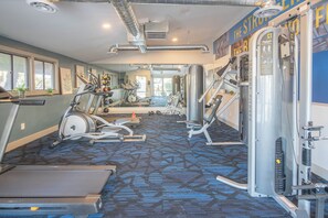 Une salle de sport équipée de tapis de course, de vélos elliptiques et de matériel de musculation.