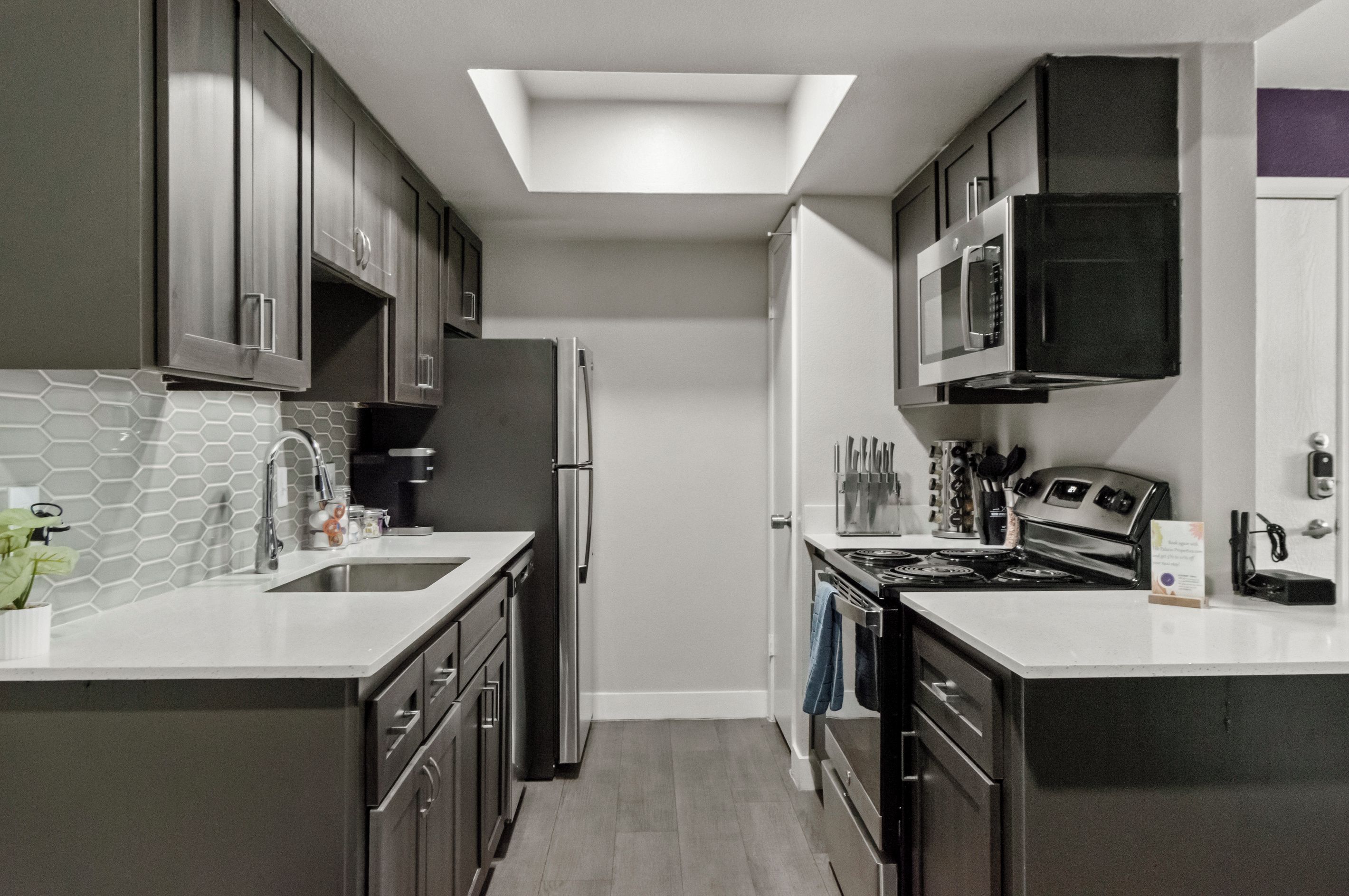 Una cocina moderna con tragaluces, electrodomésticos de acero inoxidable y encimera blanca.
