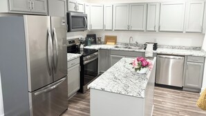 A modern kitchen with stainless steel appliances, a granite countertop, and white cabinetry. - Enjoyable 4-bedroom house with AC in charming Atlanta (Atlanta)