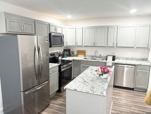 A modern kitchen with stainless steel appliances, a granite countertop, and white cabinetry. - Enjoyable 4-bedroom house with AC in charming Atlanta (Atlanta)