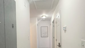 A hallway with a wooden floor, white walls, and a ceiling light fixture. - Enjoyable 4-bedroom house with AC in charming Atlanta (Atlanta)
