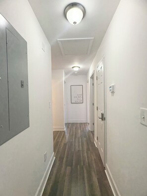 A hallway with a wooden floor, white walls, and a ceiling light fixture. - Enjoyable 4-bedroom house with AC in charming Atlanta (Atlanta)