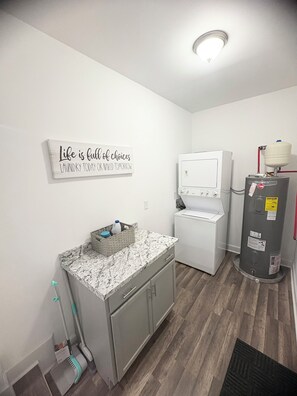 A laundry room with a white washing machine, a water heater, and a sign on the wall. - Enjoyable 4-bedroom house with AC in charming Atlanta (Atlanta)