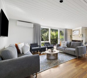 Ein modernes Wohnzimmer mit grauem Sofa, rundem Couchtisch und Kamin.