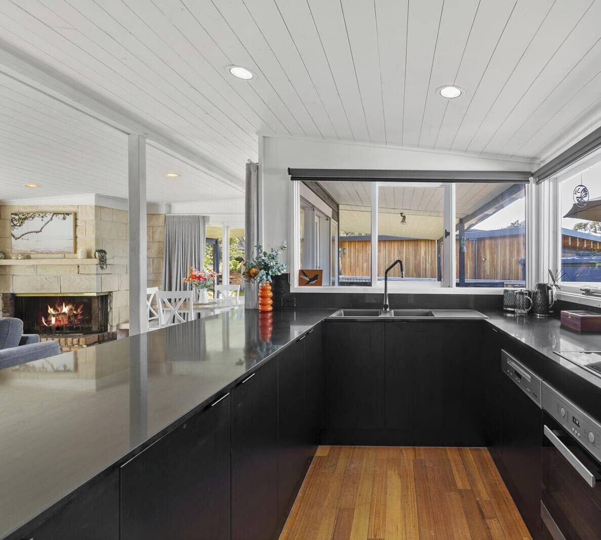 A modern kitchen with a central island, a fireplace, and large windows.