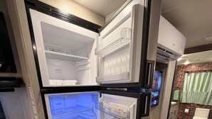Uma cozinha compacta com geladeira de portas duplas, fogão a gás e bancada de madeira.