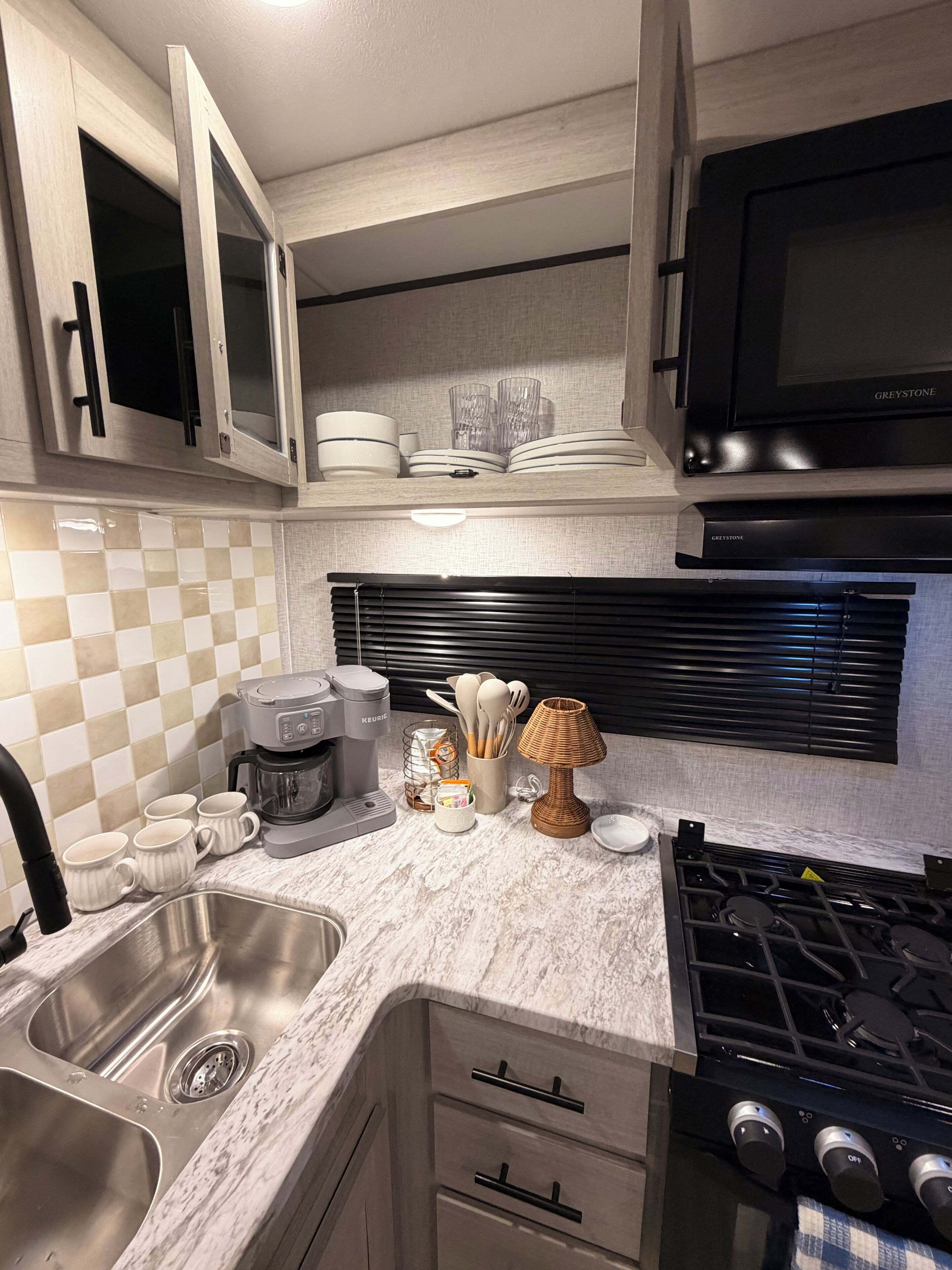 A modern kitchen with a built-in microwave, stainless steel sink, and a gas stove.