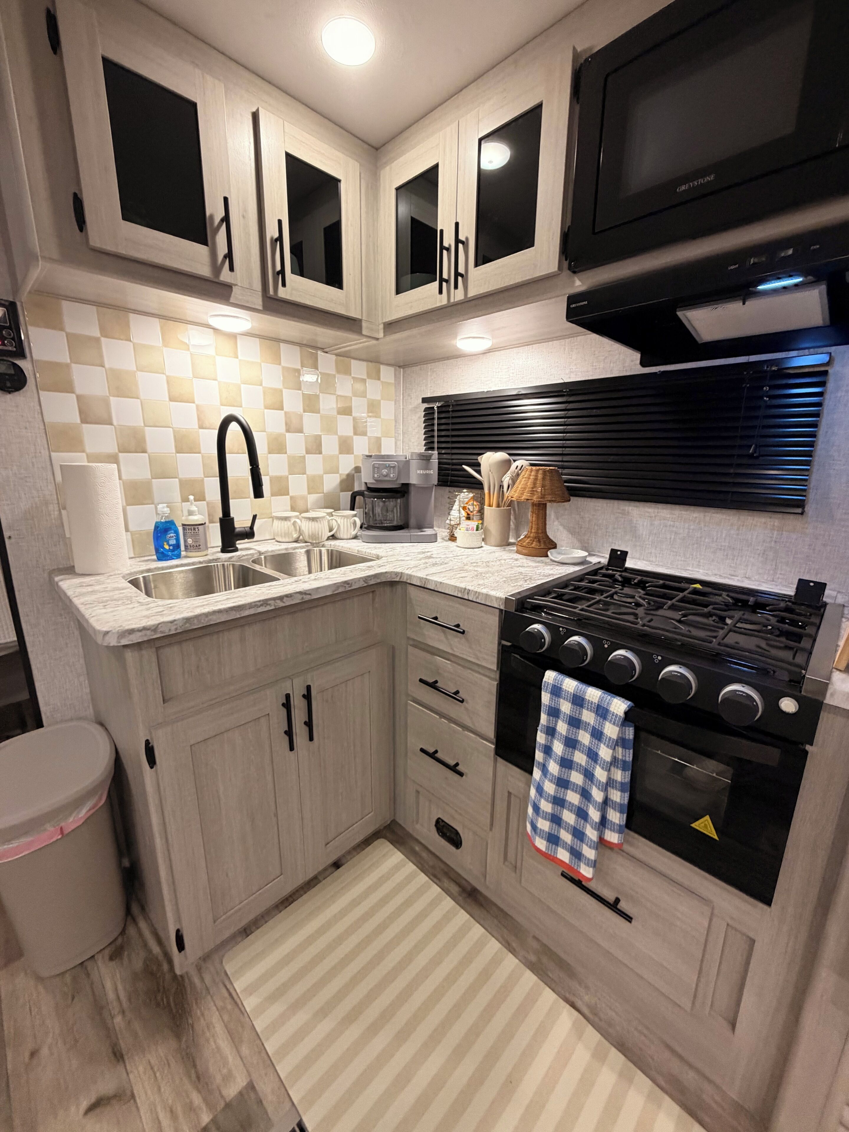 Cocina compacta con estufa a gas, microondas y cafetera.