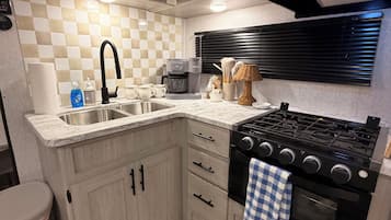 Cocina compacta con estufa a gas, microondas y cafetera.