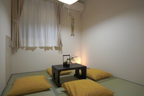 A room with a bed, a small table with a plant, and a wall-mounted air conditioner. - ANNKICHI (Nishinari Ward,Osaka)