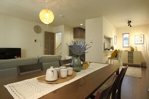 A dining area with a wooden table, chairs, a vase with flowers, and a decorative light fixture. - ANNKICHI (Nishinari Ward,Osaka)