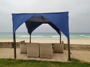 A beachside seating area with a canopy and sofas. - Seaview Hotel (Alexandria)