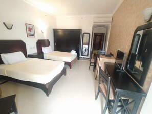 Habitación de hotel con dos camas, un escritorio con computadora y televisor.