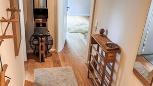 A hallway with a wooden bench, a rug, and a wooden shelf with a decorative item. - The OAK SUITE by Interhome (Bad Bederkesa)