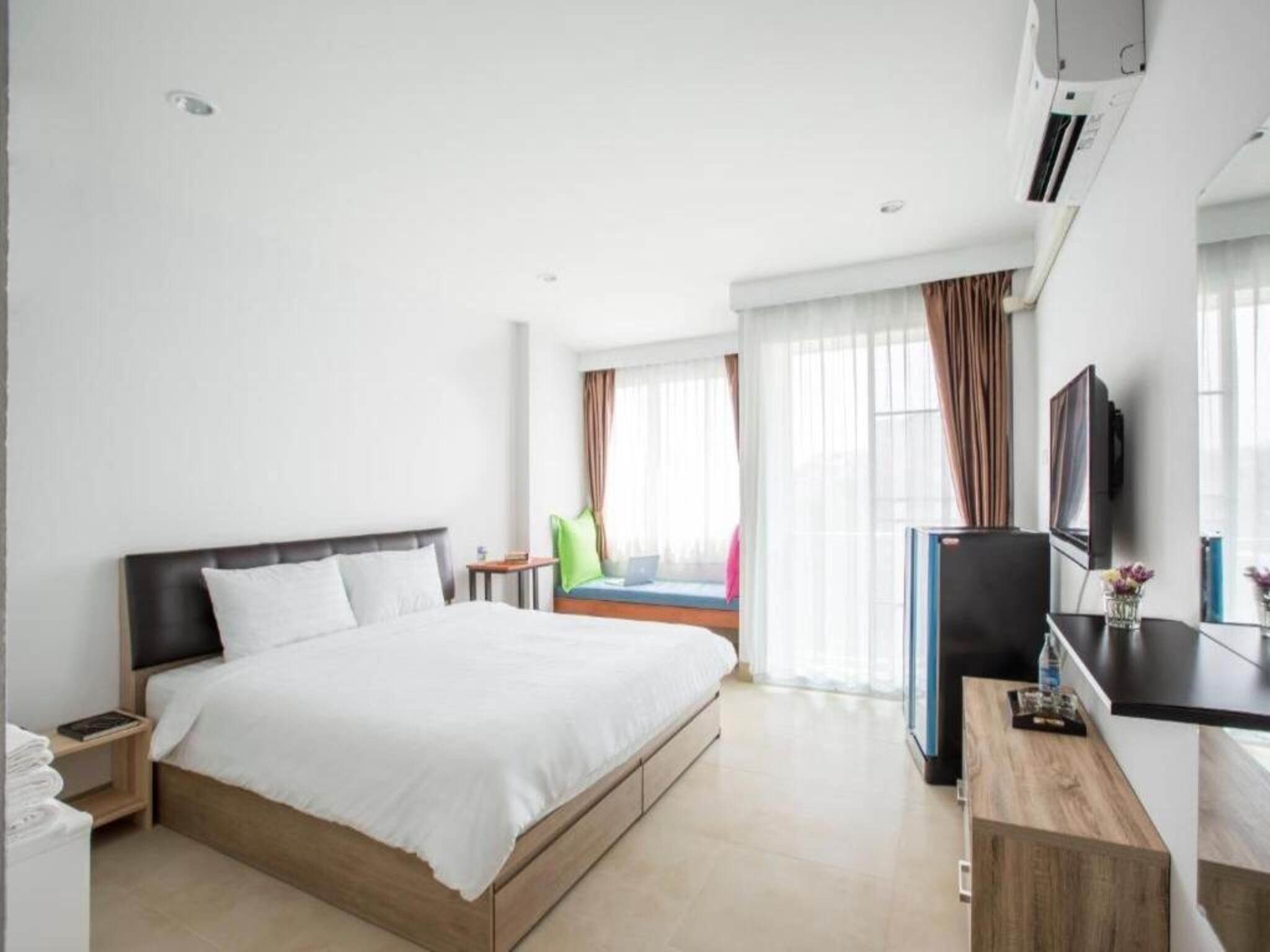 A hotel room with a bed, a desk, a television, and a window with curtains.