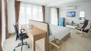 Habitación de hotel con cama, escritorio, silla, televisor y minibar.
