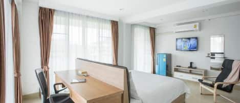 Habitación de hotel con cama, escritorio, silla, televisor y minibar.