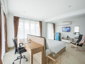A hotel room with a bed, desk, chair, TV, and a minibar. - Baan I Inspire (Phrae)