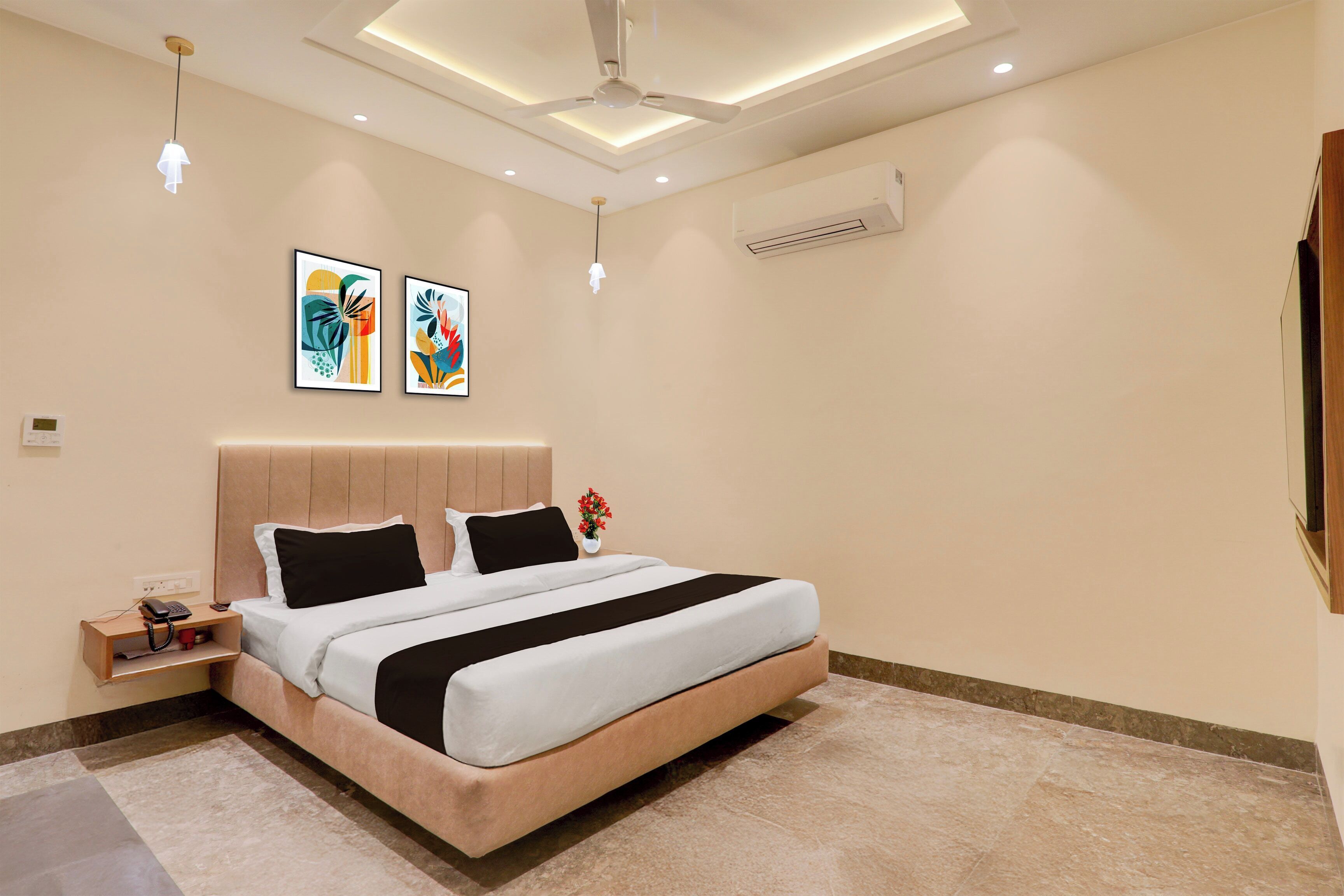 A modern bedroom with a bed, bedside tables, artwork, and an air conditioning unit.
