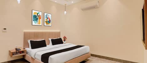 A modern bedroom with a bed, bedside tables, artwork, and an air conditioning unit.