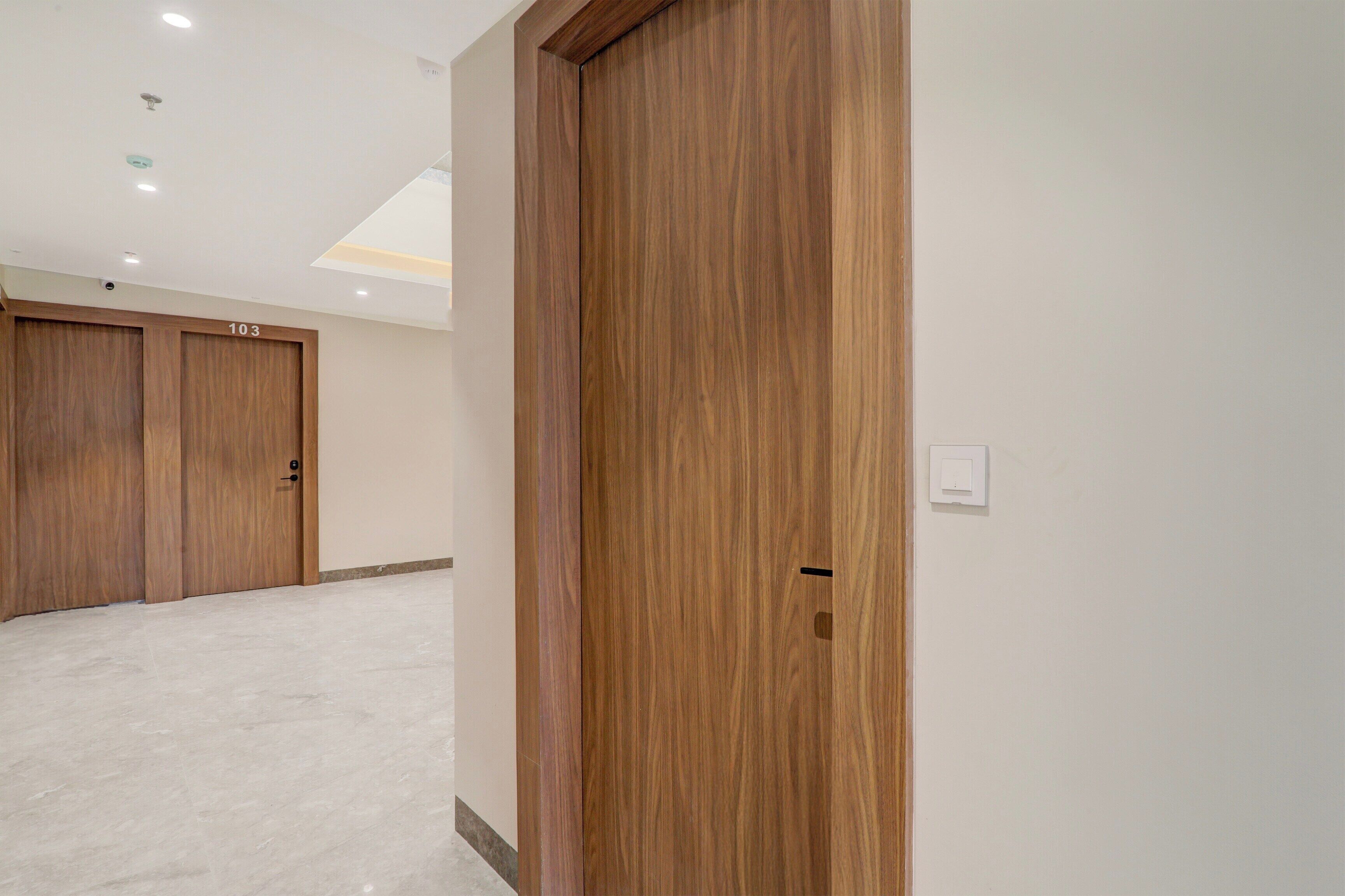 Un pasillo con puertas de madera, un interruptor de luz y un techo con iluminación empotrada.