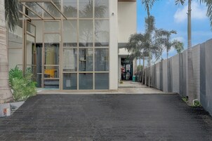 Ein modernes Gebäude mit Glasfassade, einem Betonweg und Palmen.