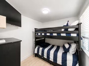 Ein Stockbett mit Schreibtisch und einem an der Wand befestigten Flachbildfernseher.