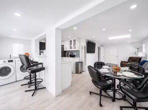 A modern kitchen with white cabinets, a central island, and a built-in oven. - Coastal Chic Retreat | Steps to the Sand (Newport Beach)