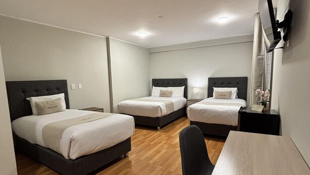 Ein Hotelzimmer mit zwei Betten, einem Schreibtisch und einem Stuhl.