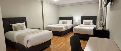 A hotel room with two beds, a desk, and a chair.