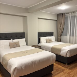 Une chambre d’hôtel avec deux lits, chacun doté d’une tête de lit, d’une table de chevet et d’une petite table.