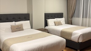 Ein Hotelzimmer mit zwei Betten, jeweils mit Kopfteil, Nachttisch und Bettablage.