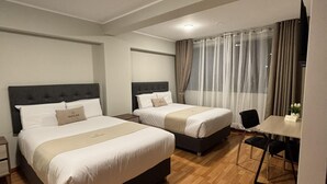Ein Hotelzimmer mit zwei Betten, einem Schreibtisch und einem Stuhl.