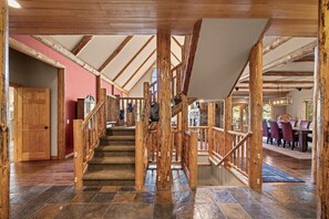 A wooden staircase with a handrail, leading to a dining area with tables and chairs. - Whitefish Lake Waterfront Retreat W/ Private Dock (Whitefish)
