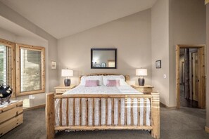 Ein Schlafzimmer mit einem hölzernen Bett, zwei Nachttischen, einem Spiegel und einem Fenster mit Jalousien.