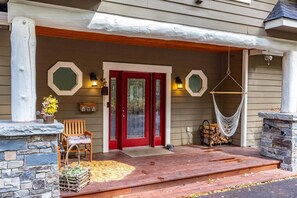 A house with a red door, a porch with a stone fireplace, and a hammock. - Whitefish Lake Waterfront Retreat W/ Private Dock (Whitefish)