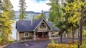 A two-story house with a dark roof, a front porch, and a driveway leading to the entrance. - Whitefish Lake Waterfront Retreat W/ Private Dock (Whitefish)