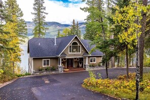 A two-story house with a dark roof, a front porch, and a driveway leading to the entrance. - Whitefish Lake Waterfront Retreat W/ Private Dock (Whitefish)