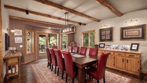 A dining area with a wooden table and red chairs, a chandelier, and framed pictures on the walls. - Whitefish Lake Waterfront Retreat W/ Private Dock (Whitefish)