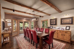 A dining area with a wooden table and red chairs, a chandelier, and framed pictures on the walls. - Whitefish Lake Waterfront Retreat W/ Private Dock (Whitefish)