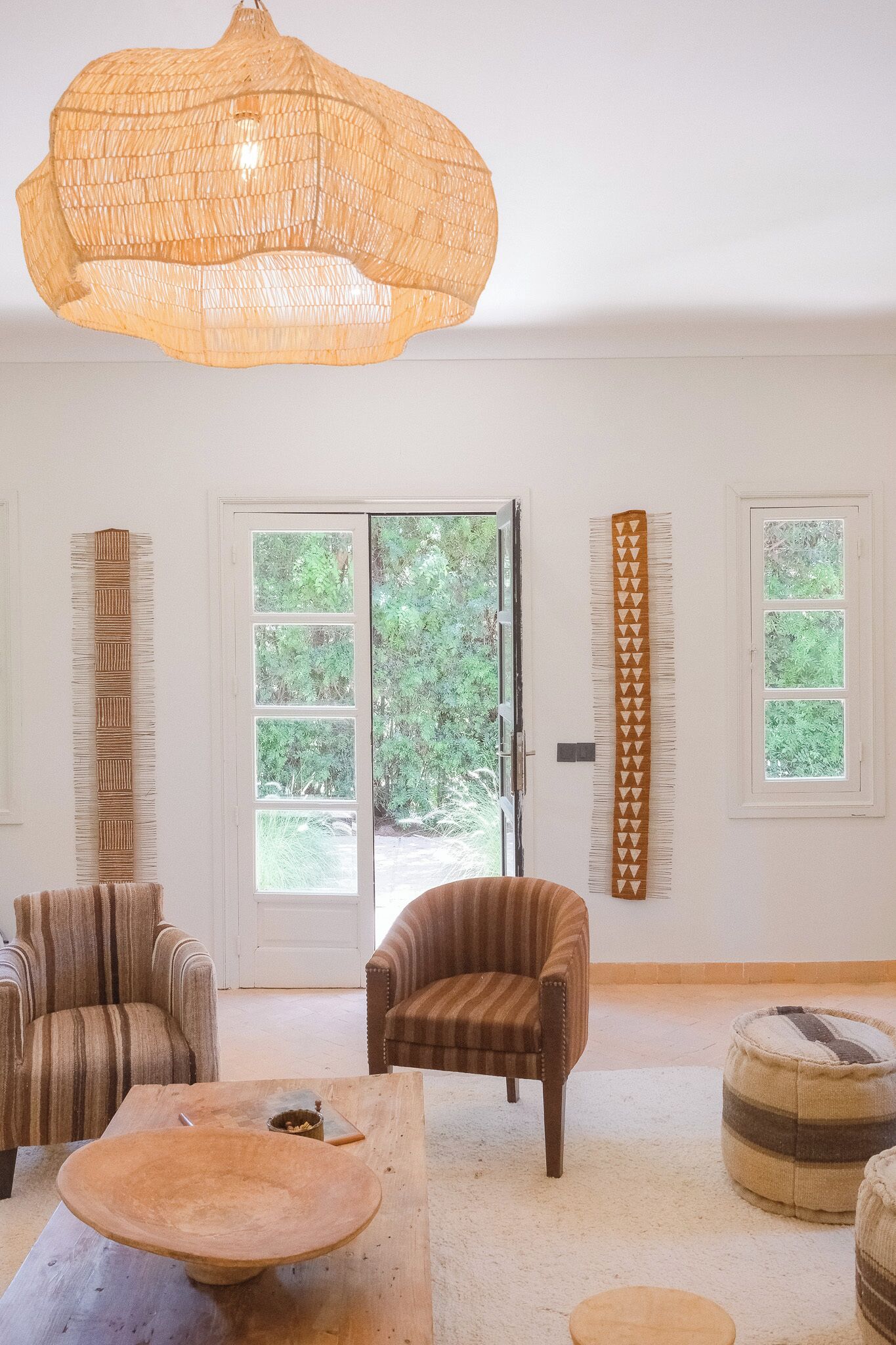 A room with a large window, a hanging light fixture, and striped furniture.