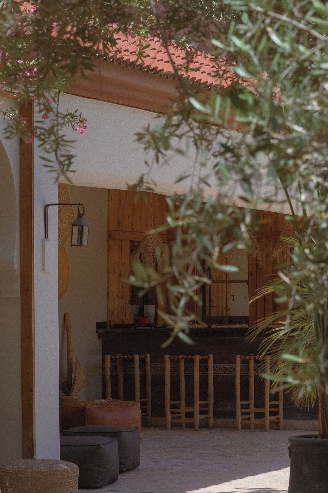 An outdoor seating area with wooden furniture, a lantern, and a potted plant.