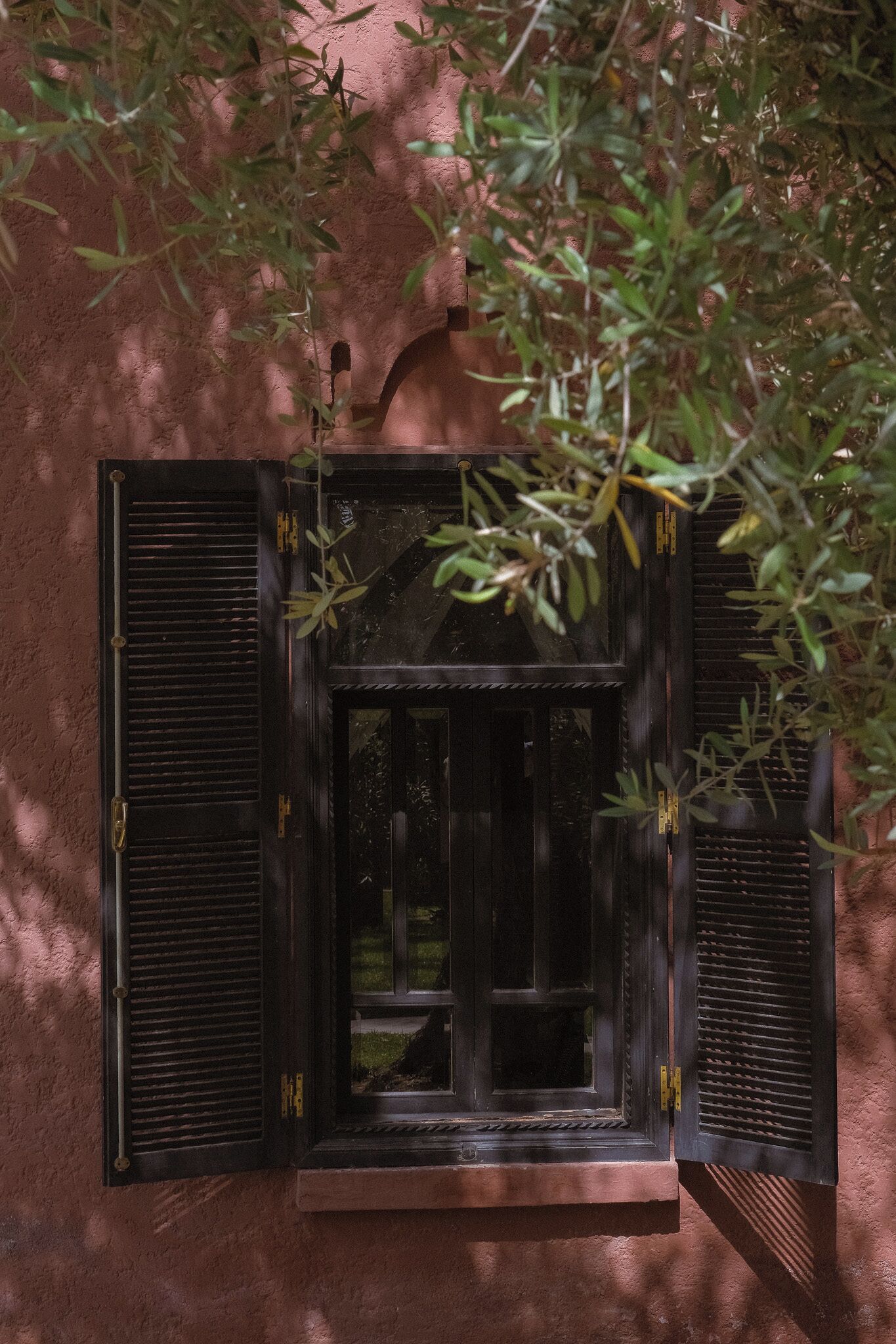 A window with a view of a garden, a door, and a small balcony area.