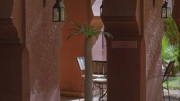 An indoor courtyard with arches, potted plants, and a sign indicating a pool.