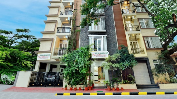 A multi-story hotel with balconies, a gated entrance, and potted plants. - Avm Comfort Inn (Bengaluru)
