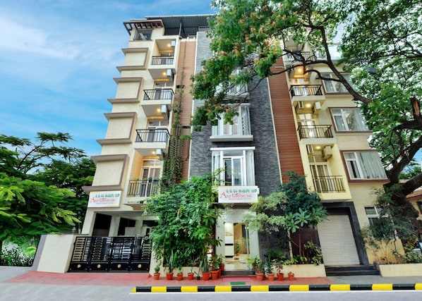A multi-story hotel with balconies, a gated entrance, and potted plants. - Avm Comfort Inn (Bengaluru)