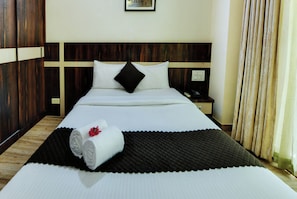 A hotel room with a large bed, a nightstand, a telephone, and a window with curtains. - Avm Comfort Inn (Bengaluru)