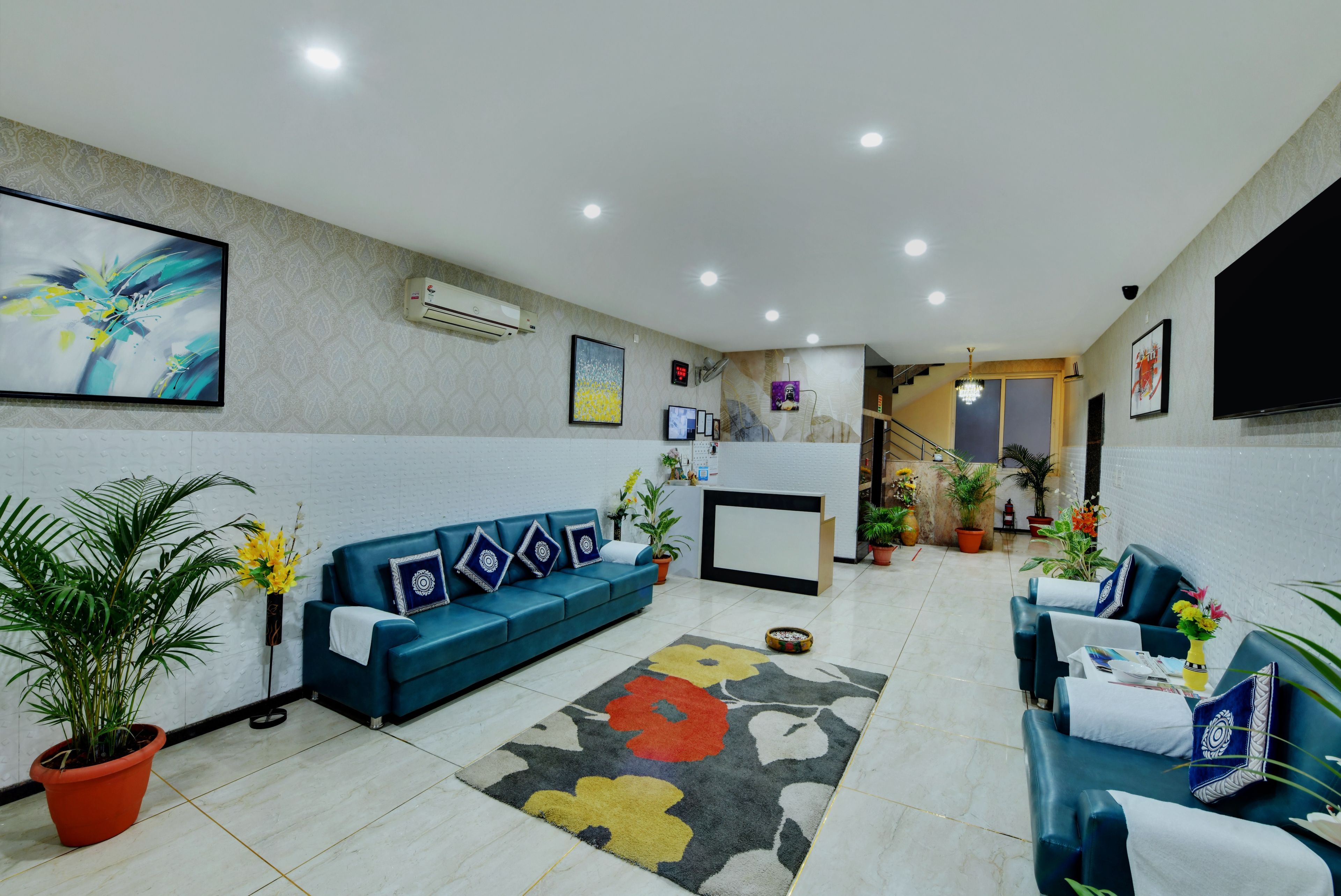 A reception area with a blue sofa, a reception desk, potted plants, and artwork on the walls.